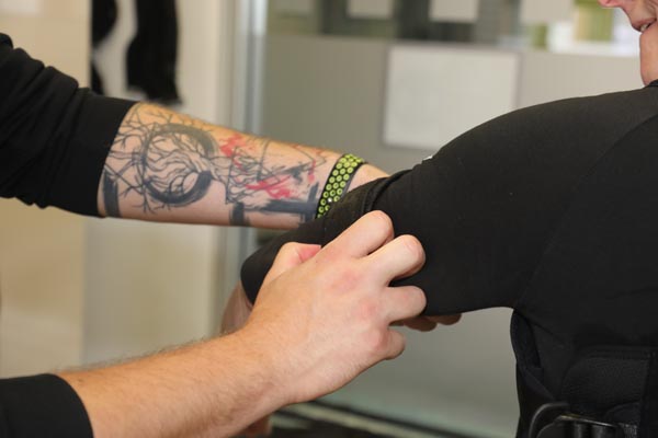 Der Sporttherapeut schließt die Arm-Elektroden beim Kunden an.